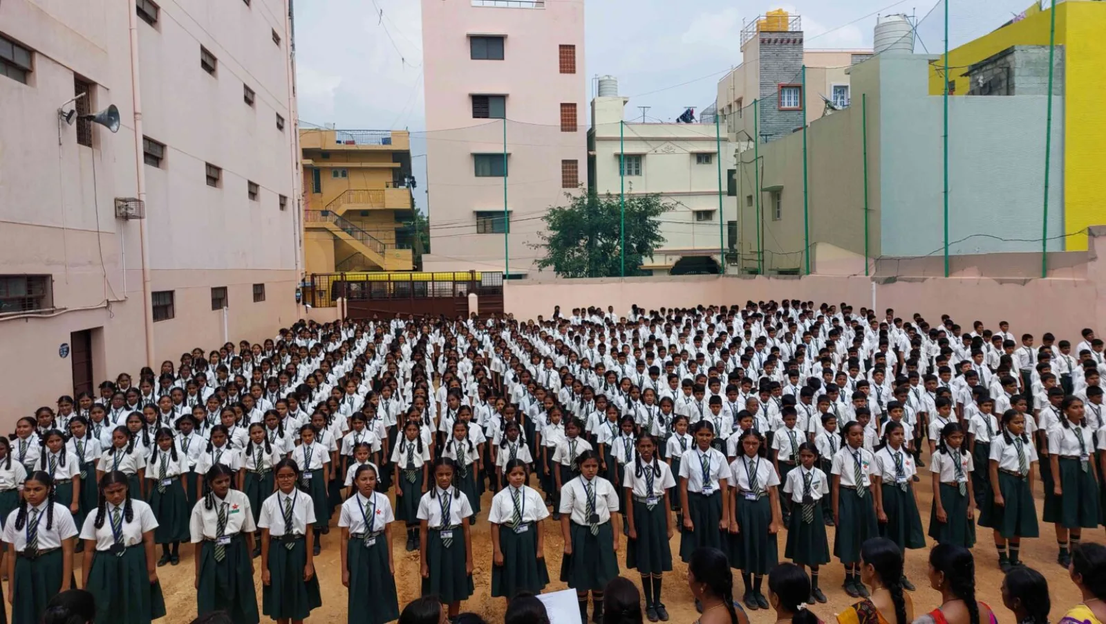 Hundreds of students in school uniform standing in formation for morning assembly on the school ground