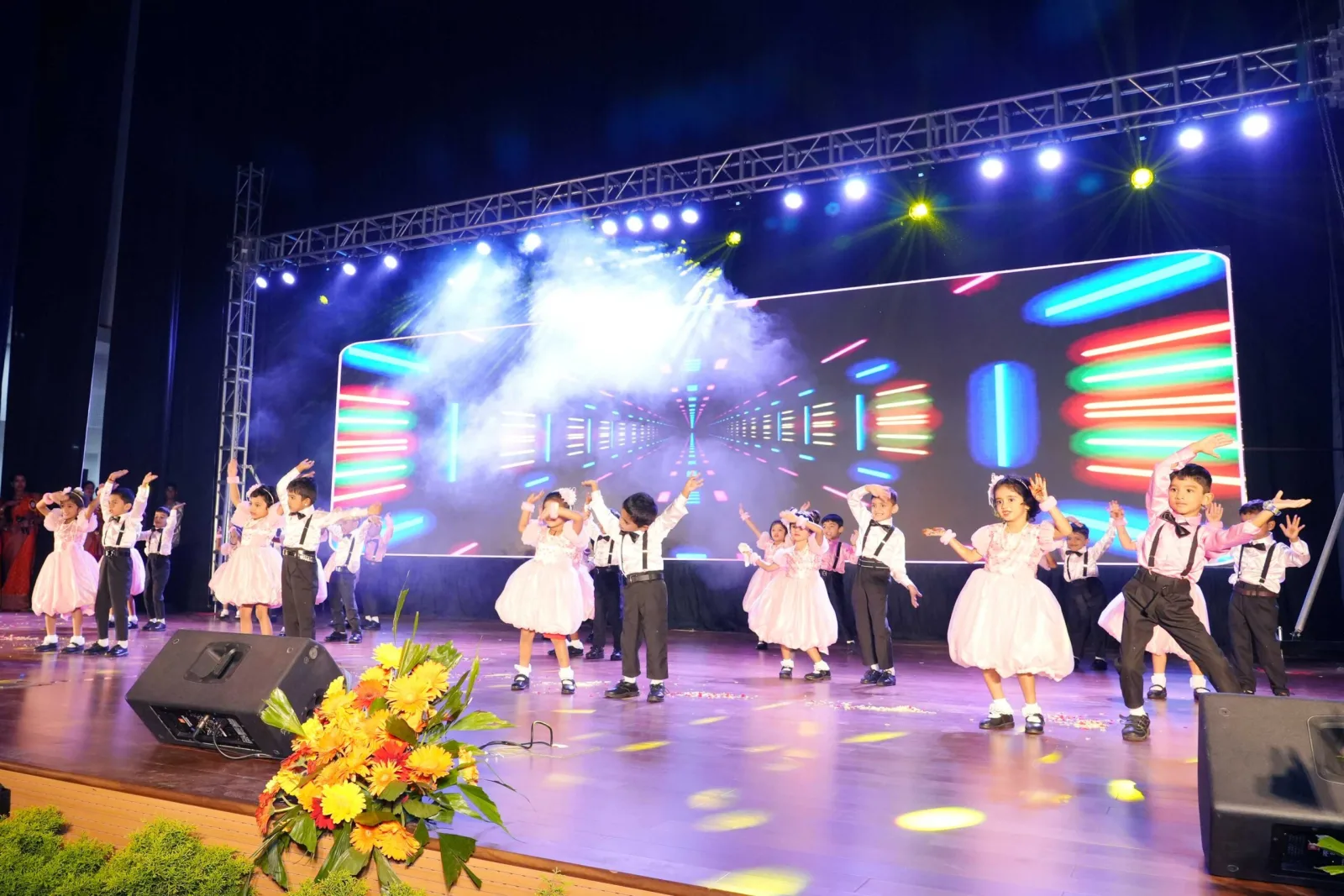 Two students in golden costume performing a duet dance on the Annual Day stage