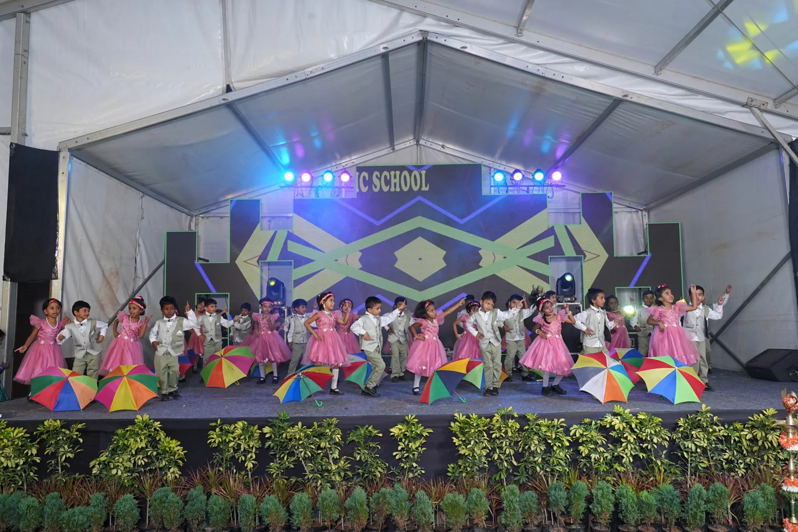 Students in colourful costume dancing on stage with kite-shaped stage decor