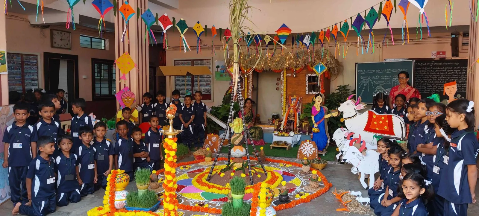 Students in blue uniform gathered around a decorated rangoli display