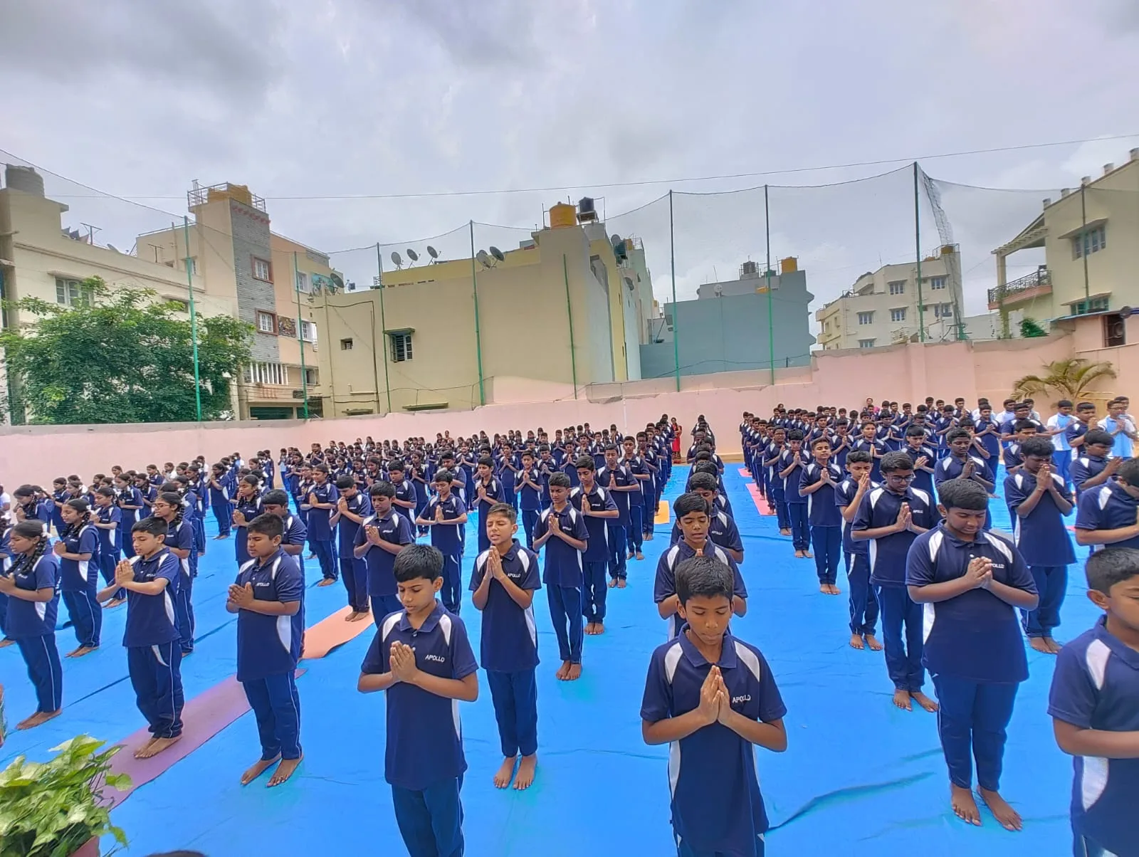 A large group of students standing with hands folded in prayer during a morning assembly