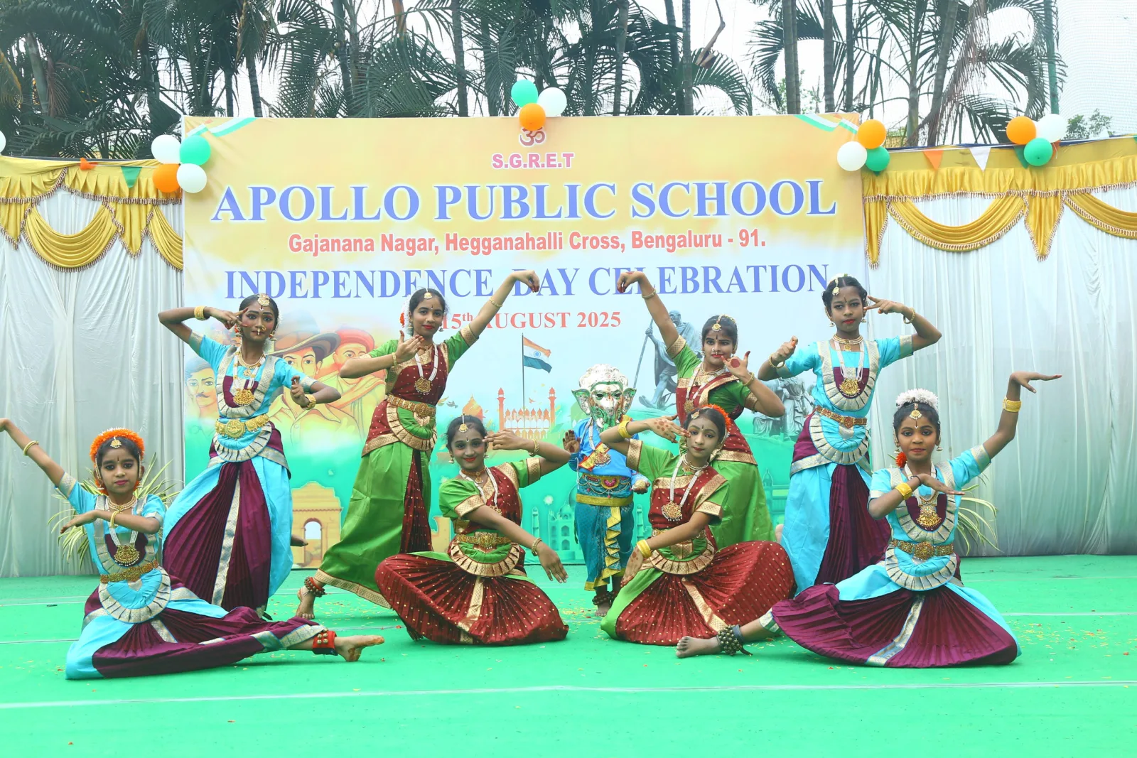Students in traditional costume performing a patriotic dance on a decorated outdoor stage