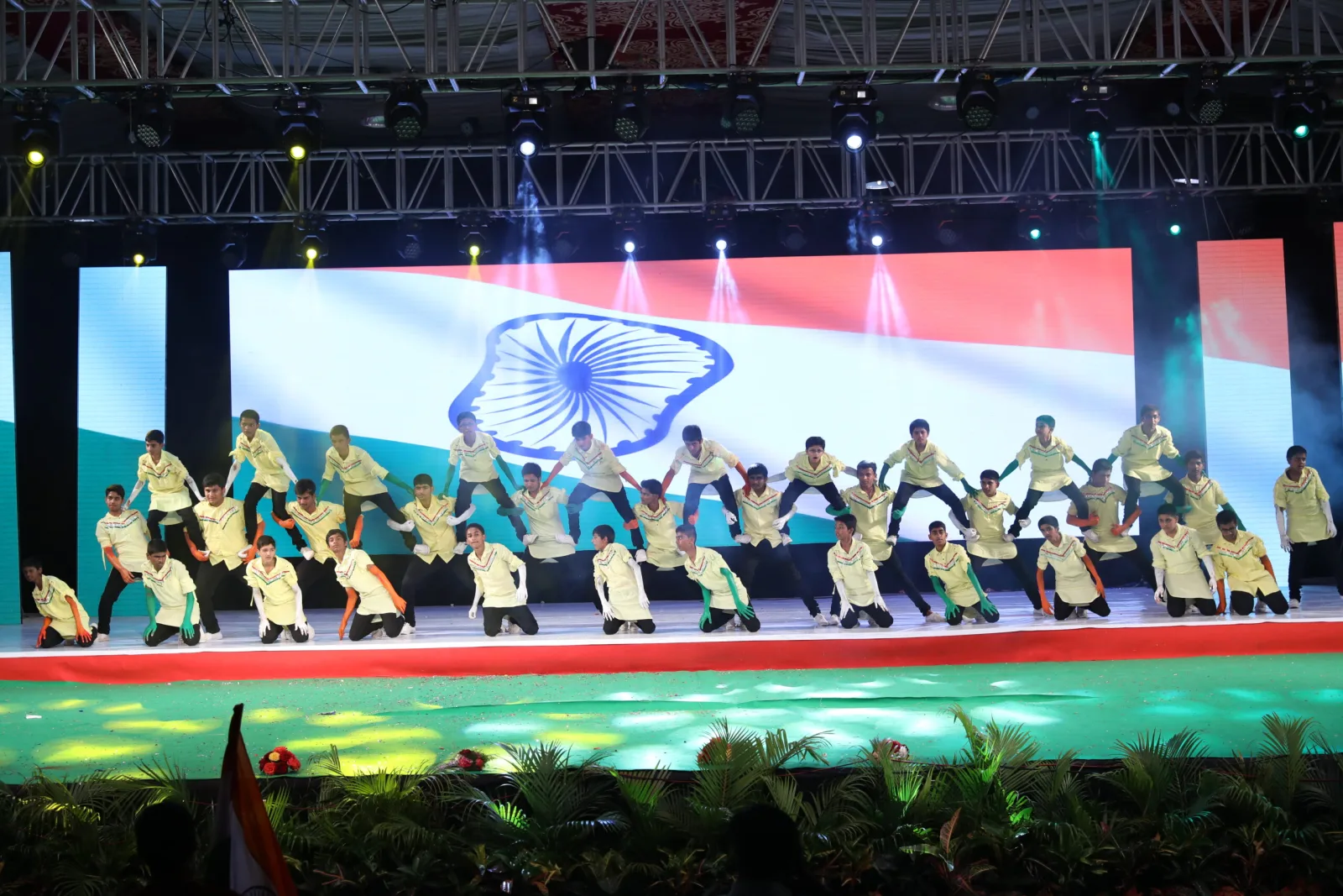 Boys in matching costume performing an acrobatic formation dance on stage
